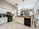 Open kitchen boasts white cabinets, granite countertops, black appliances, and stylish pendant lighting at 24112 Robinwood St, Leesburg, FL 34748