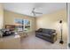 Bedroom featuring a gray sofa, desk, ceiling fan, and natural light from the window at 2428 Maverick Way, The Villages, FL 32162
