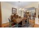 Elegant dining room with a rustic table, chandelier, and hardwood floors, open to the kitchen at 2428 Maverick Way, The Villages, FL 32162