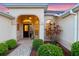 Inviting front entrance with an arched porch, manicured landscaping, and a decorative glass front door at 2428 Maverick Way, The Villages, FL 32162