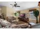 Comfortable living room with hardwood floors, floral couches, ceiling fan and a large television at 2428 Maverick Way, The Villages, FL 32162