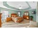 Main bedroom with tray ceiling, fan, light green walls, and carpet flooring at 2428 Maverick Way, The Villages, FL 32162