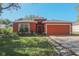 Charming single-story home featuring a well-maintained lawn and a two-car garage with a warm, inviting orange facade at 2442 Foxhollow Rd, Tavares, FL 32778