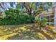 A vibrant backyard featuring a lush lawn and mature trees, offering a serene outdoor space at 2488 Ansley Path, The Villages, FL 32162