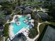 Aerial view showcasing the community pool, tennis courts, parking, and tropical landscaping with palm trees at 27121 Greenfly Orchid Ln, Leesburg, FL 34748
