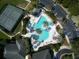 Aerial view of a community pool, tennis court, and ample parking, surrounded by palm trees and lush landscape at 27121 Greenfly Orchid Ln, Leesburg, FL 34748