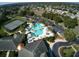 Aerial view of a resort-style community pool, tennis courts, lush landscaping, and a spacious parking lot at 27121 Greenfly Orchid Ln, Leesburg, FL 34748