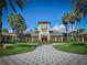Beautiful clubhouse with clock tower, lush landscaping, and a paver walkway at 27121 Greenfly Orchid Ln, Leesburg, FL 34748