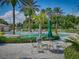 Inviting community pool area with tables, chairs, lush landscaping, and various palm trees at 27121 Greenfly Orchid Ln, Leesburg, FL 34748