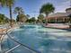 Community pool featuring various seating options, palm trees, and a nearby clubhouse at 27121 Greenfly Orchid Ln, Leesburg, FL 34748