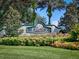 Landscaped community entrance sign with manicured hedges and flowers, and tall palm trees against a blue sky at 27121 Greenfly Orchid Ln, Leesburg, FL 34748