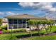 Exterior of home featuring a screened-in lanai, well-maintained landscaping, and vibrant flower accents at 27121 Greenfly Orchid Ln, Leesburg, FL 34748