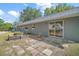 View of the side of a one-story house with gray exterior, a sliding glass door, and a small tiled patio at 331 W Lewis Ave, Apopka, FL 32712