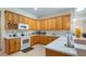 Bright kitchen with wood cabinets, white appliances, and light countertops, offering ample counter space at 3728 Mulberry Grove Loop, Leesburg, FL 34748