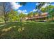 Expansive front lawn and beautiful home surrounded by lush greenery and mature trees on a sunny day at 39636 Carolina Ave, Lady Lake, FL 32159