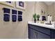 Stylish bathroom featuring a modern vanity with gold fixtures, dark blue cabinets and decorative towels at 5397 Marshelder St, Apopka, FL 32712