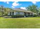 Well-manicured backyard featuring lush green grass, mature trees, and a screened lanai at 6106 Spinnaker Loop, Lady Lake, FL 32159