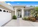 Elegant home entrance featuring decorative columns, a modern glass door, and manicured landscaping at 6106 Spinnaker Loop, Lady Lake, FL 32159