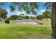 Scenic view of a tranquil pond surrounded by lush greenery and mature trees in a well-maintained community at 6106 Spinnaker Loop, Lady Lake, FL 32159