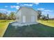 View of a metal building with a white door, garage door and concrete entrance on expansive green property at 6679 Cr 613, Bushnell, FL 33513