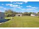 Spacious lot with lush green grass, and scattered trees. Includes metal building and a house in the background at 6679 Cr 613, Bushnell, FL 33513