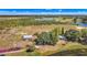 Expansive aerial view showcasing property with home, outbuildings, lake, and surrounding groves at 6988 Blue Cedar Rd, Leesburg, FL 34748