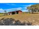 Rustic red barn with adjacent shed area in a rural setting, surrounded by grassy land and trees at 6988 Blue Cedar Rd, Leesburg, FL 34748
