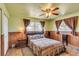 Comfortable bedroom featuring wood paneling, ceiling fan, and natural light from the double-paned windows at 6988 Blue Cedar Rd, Leesburg, FL 34748