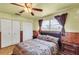 Comfortable bedroom featuring wood paneling, ceiling fan, and natural light from the window at 6988 Blue Cedar Rd, Leesburg, FL 34748