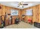 Home office with wood walls, large window, and classic wooden desk setup at 6988 Blue Cedar Rd, Leesburg, FL 34748