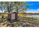 Exterior view of red shed and a tranquil waterfront view with mature trees at 6988 Blue Cedar Rd, Leesburg, FL 34748