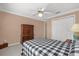 Bedroom with neutral walls features a dark wood dresser, white closet, and a comfy checkered comforter at 733 Palma Dr, The Villages, FL 32159