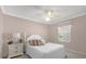 Cozy bedroom with white furnishings including a bed with floral pillows, a fan, and natural light from the window at 733 Palma Dr, The Villages, FL 32159