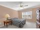 Relaxing bedroom with a checkered comforter, side table with lamp, and bright natural light from the window at 733 Palma Dr, The Villages, FL 32159
