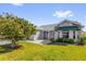 Well-maintained single-story home featuring a landscaped lawn, gray siding, and an inviting covered entrance on a sunny day at 733 Palma Dr, The Villages, FL 32159