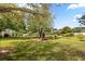 This backyard boasts a large tree, lush lawn, and garden area at 7636 Lake Angelina Dr, Mount Dora, FL 32757