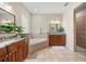 Bright bathroom featuring double vanities, a soaking tub, granite countertops, and wood cabinetry at 7636 Lake Angelina Dr, Mount Dora, FL 32757