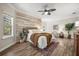Cozy bedroom with a wood-accent wall, ceiling fan, decorative rug, and comfortable sitting area at 7636 Lake Angelina Dr, Mount Dora, FL 32757