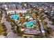 Aerial view of a community pool area surrounded by palm trees, landscaping, buildings and parking at 9905 Gobat Aly, Orlando, FL 32827