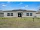 Backyard showcasing a home fitted with solar panels and a well-maintained lawn at 197 Pineywoods St, St Cloud, FL 34772