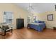 A serene bedroom featuring a blue bed set, a tall dresser, a sitting chair and hardwood floors at 2186 Quinn Ln, The Villages, FL 32162