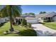 Charming single-story home with a well-manicured lawn, a palm tree, and a two-car garage at 2186 Quinn Ln, The Villages, FL 32162