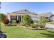 Well-manicured lawn with mature plants leading to a charming home and a two-car garage at 2186 Quinn Ln, The Villages, FL 32162