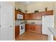 Traditional kitchen design with wooden cabinets, white appliances, neutral countertops and wood-look flooring at 2186 Quinn Ln, The Villages, FL 32162