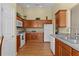 Traditional kitchen design with wooden cabinets, white appliances, neutral countertops and wood-look flooring at 2186 Quinn Ln, The Villages, FL 32162