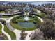 Aerial view of the community clubhouse with ponds, fountain, mature landscaping, and a paved road at 2982 Lake Huron Ln, Tavares, FL 32778