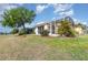 View of the screened lanai overlooking the manicured backyard with a mature tree on a sunny day at 2982 Lake Huron Ln, Tavares, FL 32778