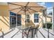 This covered patio features an umbrella covered table and chairs with sliding door access to the home at 2982 Lake Huron Ln, Tavares, FL 32778