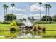 Scenic water feature with a pond, waterfall, and fountain surrounded by lush landscaping and tall palm trees on a sunny day at 2982 Lake Huron Ln, Tavares, FL 32778