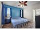 A blue bedroom features dark wood-look floors, a ceiling fan, and lots of natural light at 34448 Tuscany Ave, Sorrento, FL 32776